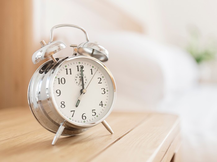 Alarm clock sitting on a bedside table.