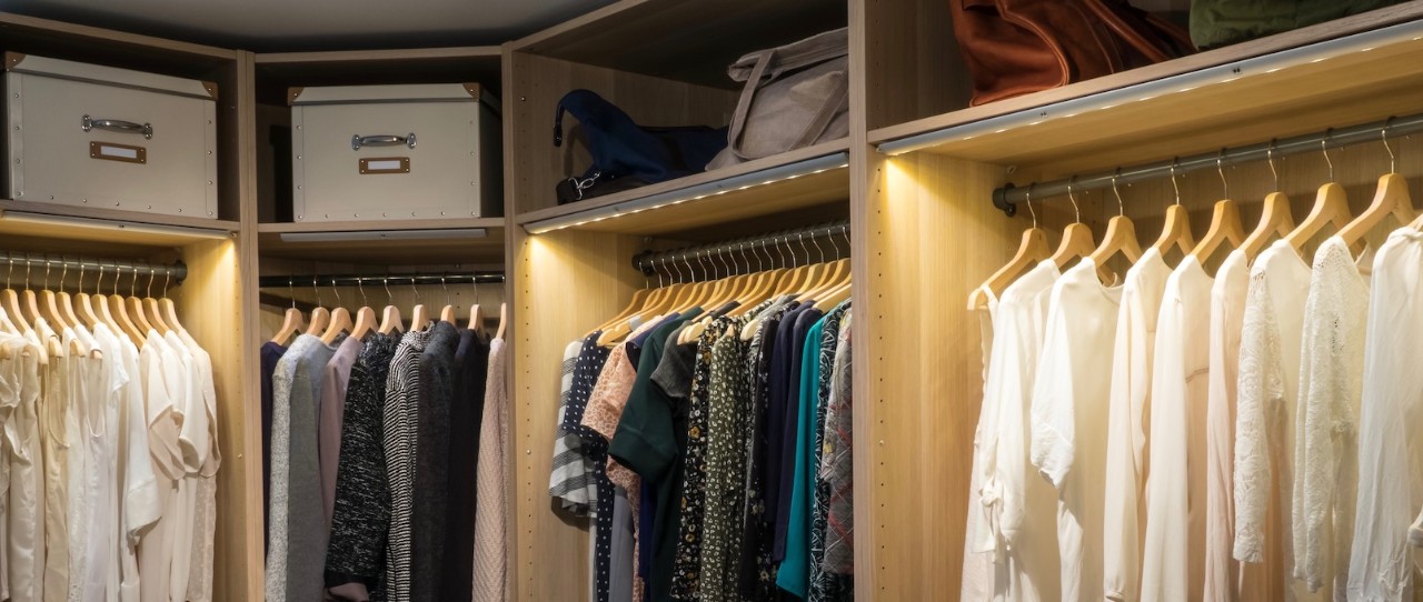 Large organized closet with white clothing on one side and prints in the middle